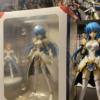Anime figure displayed beside its original retail box with visible light shelf wear and softened edges